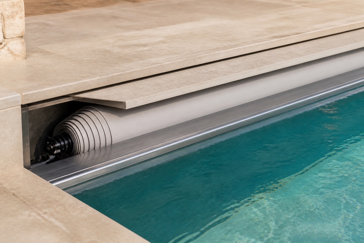 Recessed automatic pool cover housing and track along a stone deck.